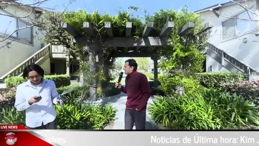 Interview scene in a lush outdoor garden with two men, one holding a microphone, under a pergola on.